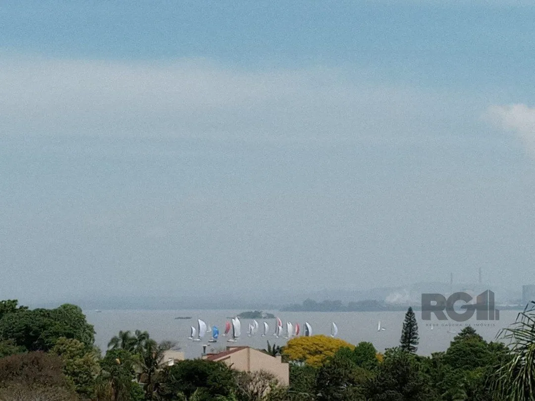 Imagem residência com vista panorâmica espetacular para o Guaíba em todos os cômodos da casa, hall de entrada, gabinete, lavabo, living para três ambientes com sacada e vista