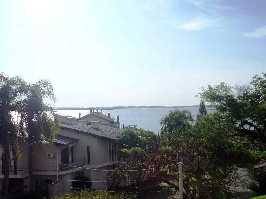 Imagem residência com vista panorâmica espetacular para o Guaíba em todos os cômodos da casa, hall de entrada, gabinete, lavabo, living para três ambientes com sacada e vista